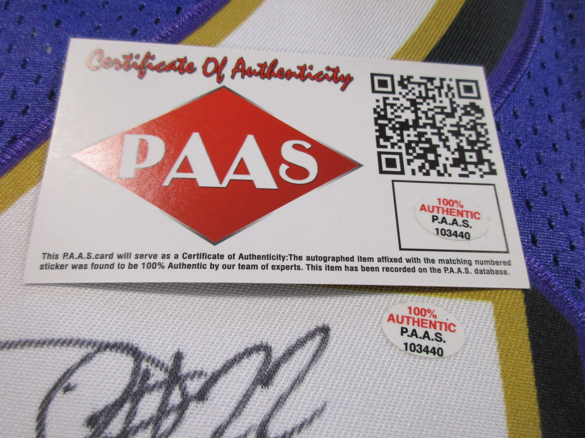 Close-up of PAAS Certificate of Authenticity card and matching numbered hologram sticker on the jersey