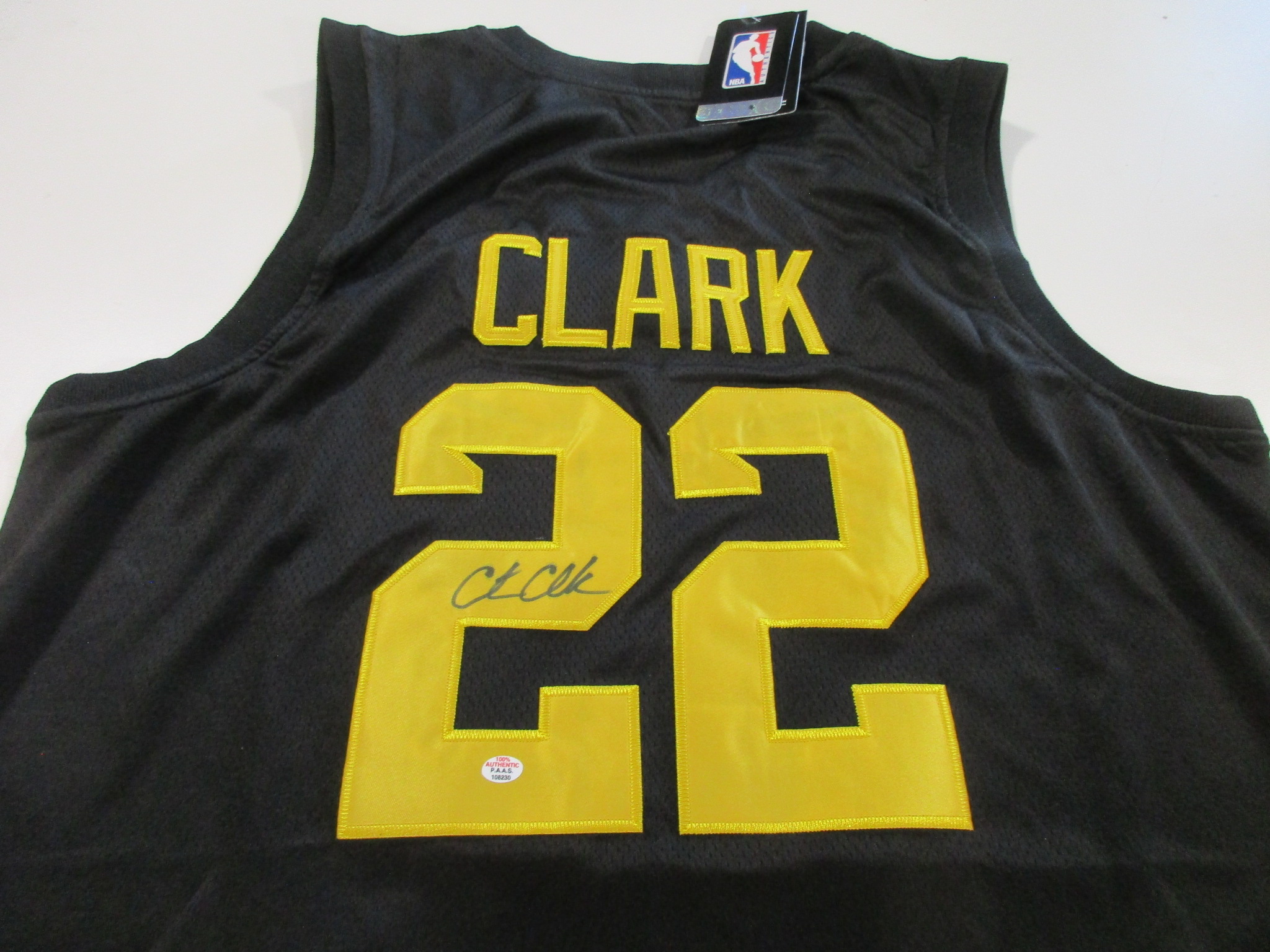 Black Iowa Hawkeyes jersey with CLARK nameplate, number 22, and black marker signature across the numeral, NBA hangtag attached