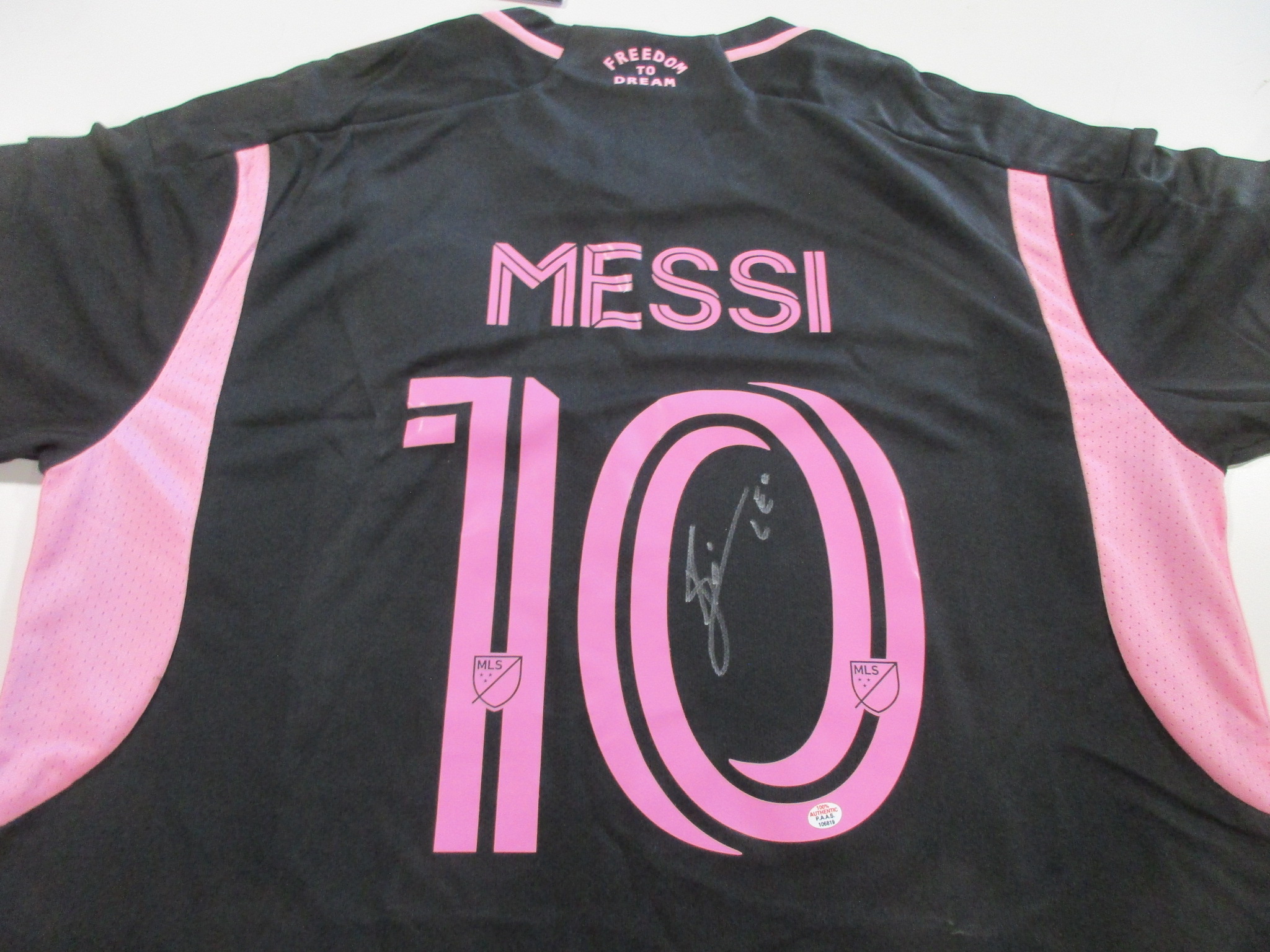 Back of black and pink Inter Miami jersey with MESSI No. 10 and a silver-tone signature over the numeral