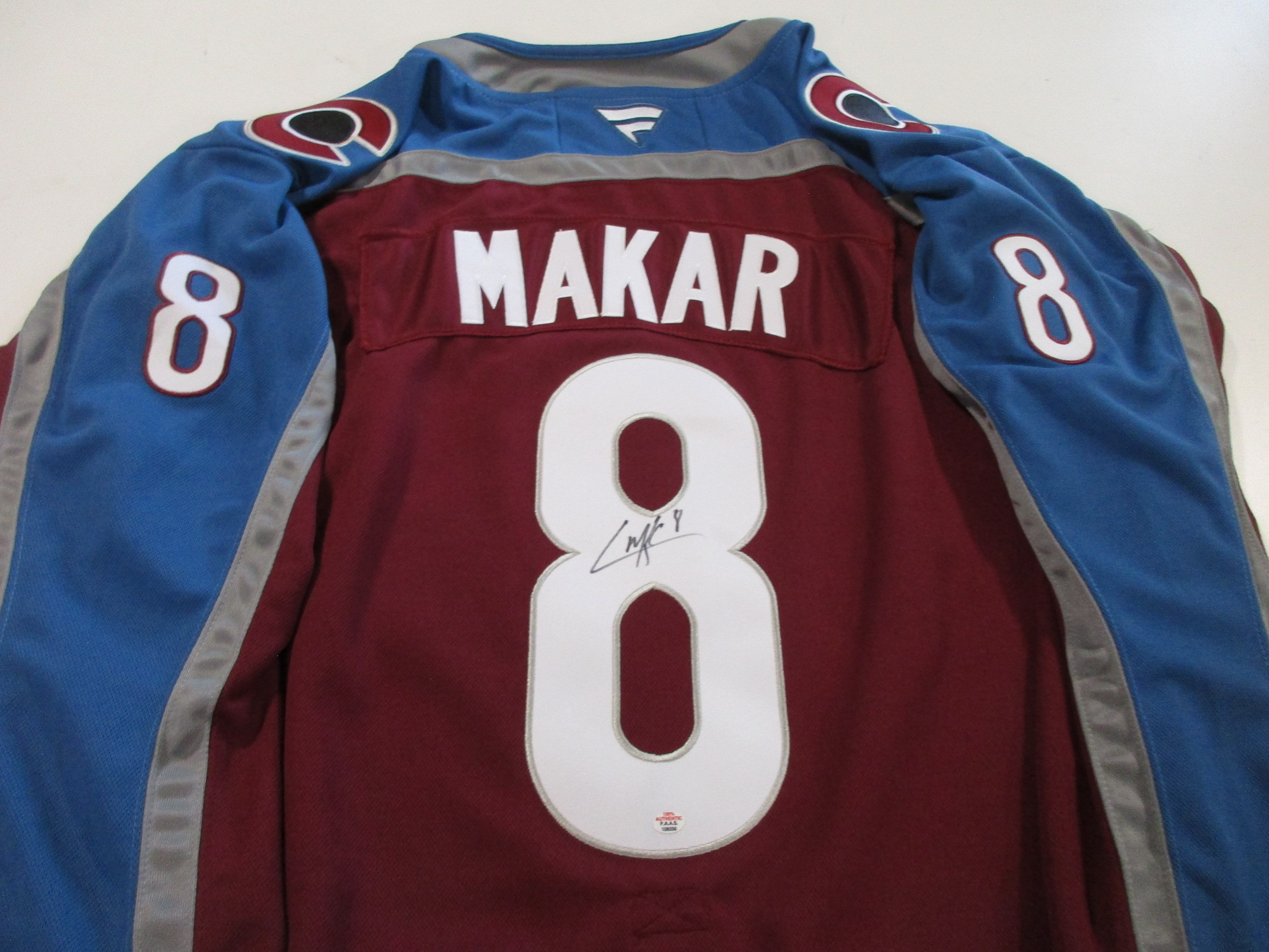 Colorado Avalanche burgundy and blue hockey jersey with MAKAR nameplate and number 8, showing an inked signature on the back