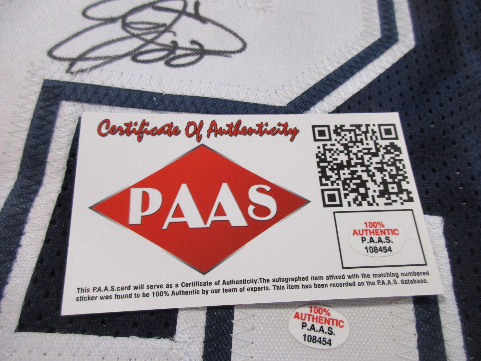 Close-up of a P.A.A.S. Certificate of Authenticity card and matching numbered sticker affixed to the jersey