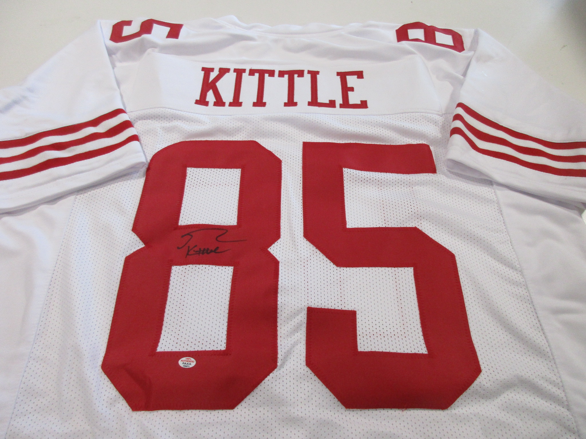 Back view of white 49ers jersey number 85 with KITTLE nameplate and a signature on the number 8