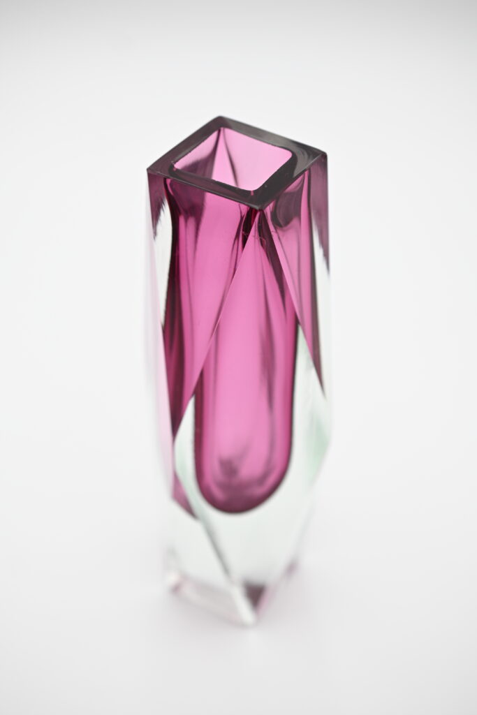 Overhead angled view into faceted pink glass vase opening showing color layering
