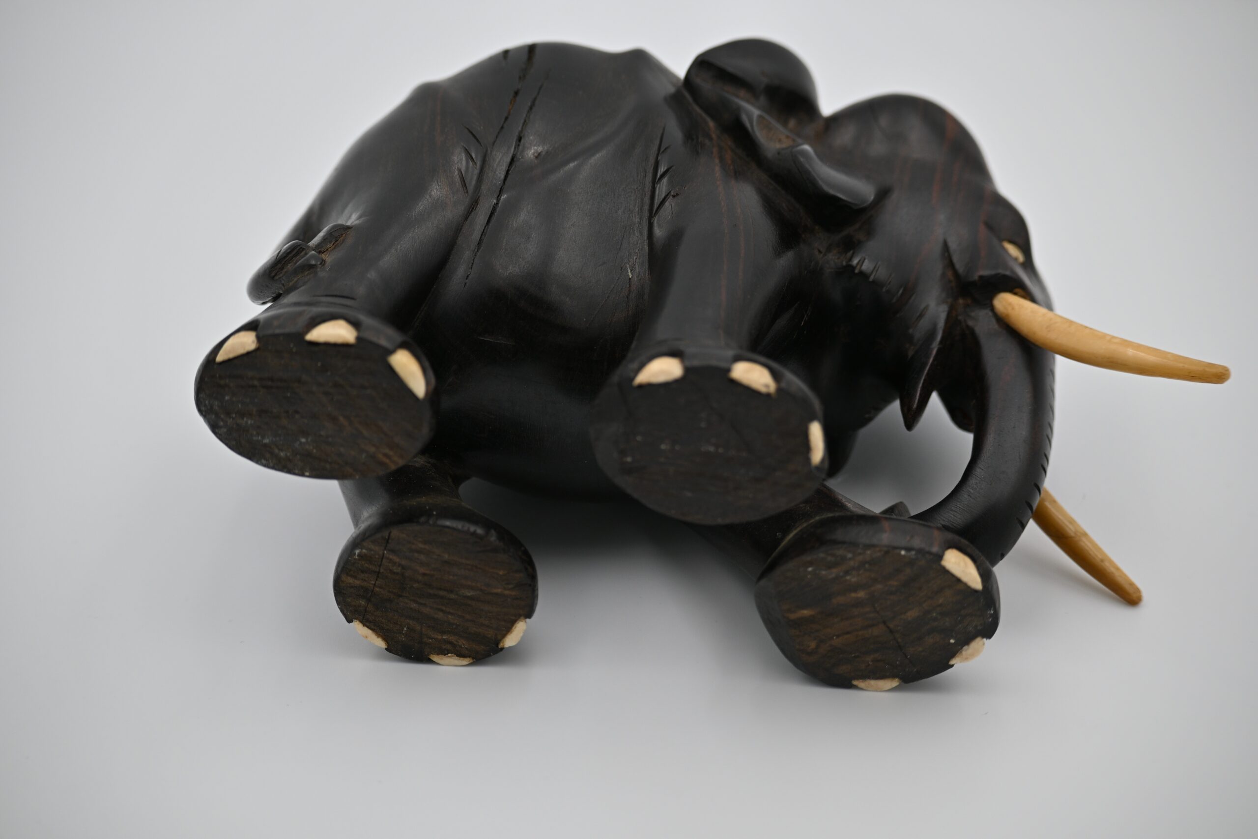 Low angle view of the elephant figurine's underside showing carved feet with pale toenail accents