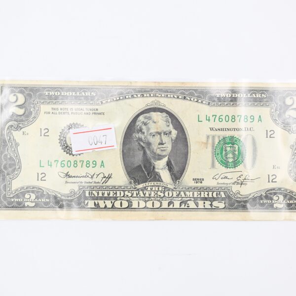 Close-up of the two-dollar note face with a small paper price tag numbered 0047 attached near the portrait