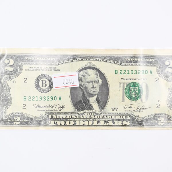 Close-up of the two-dollar note face with a small paper price tag numbered 0048 placed over the portrait