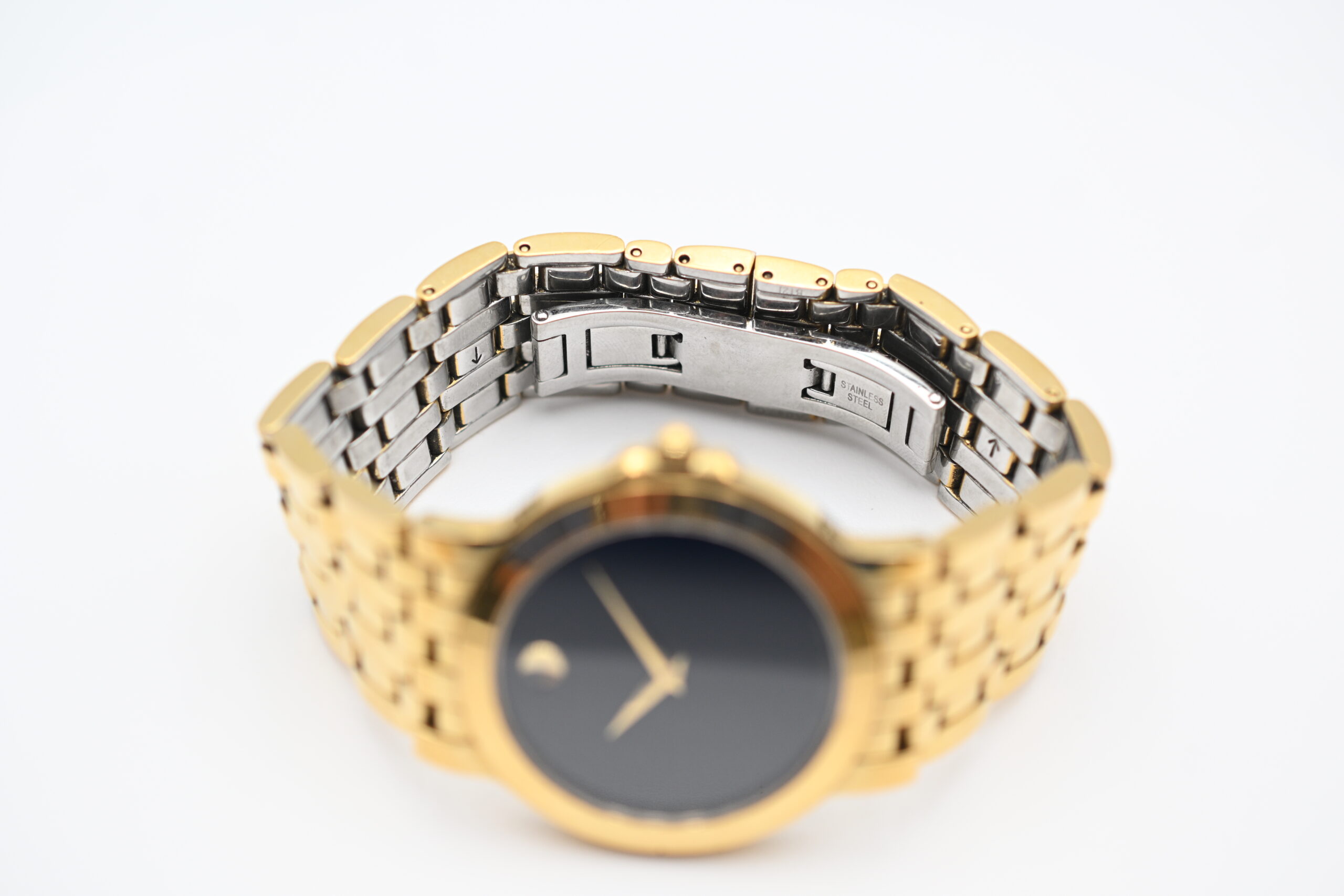 Movado watch tilted to show the open bracelet clasp and stainless steel underside of the links