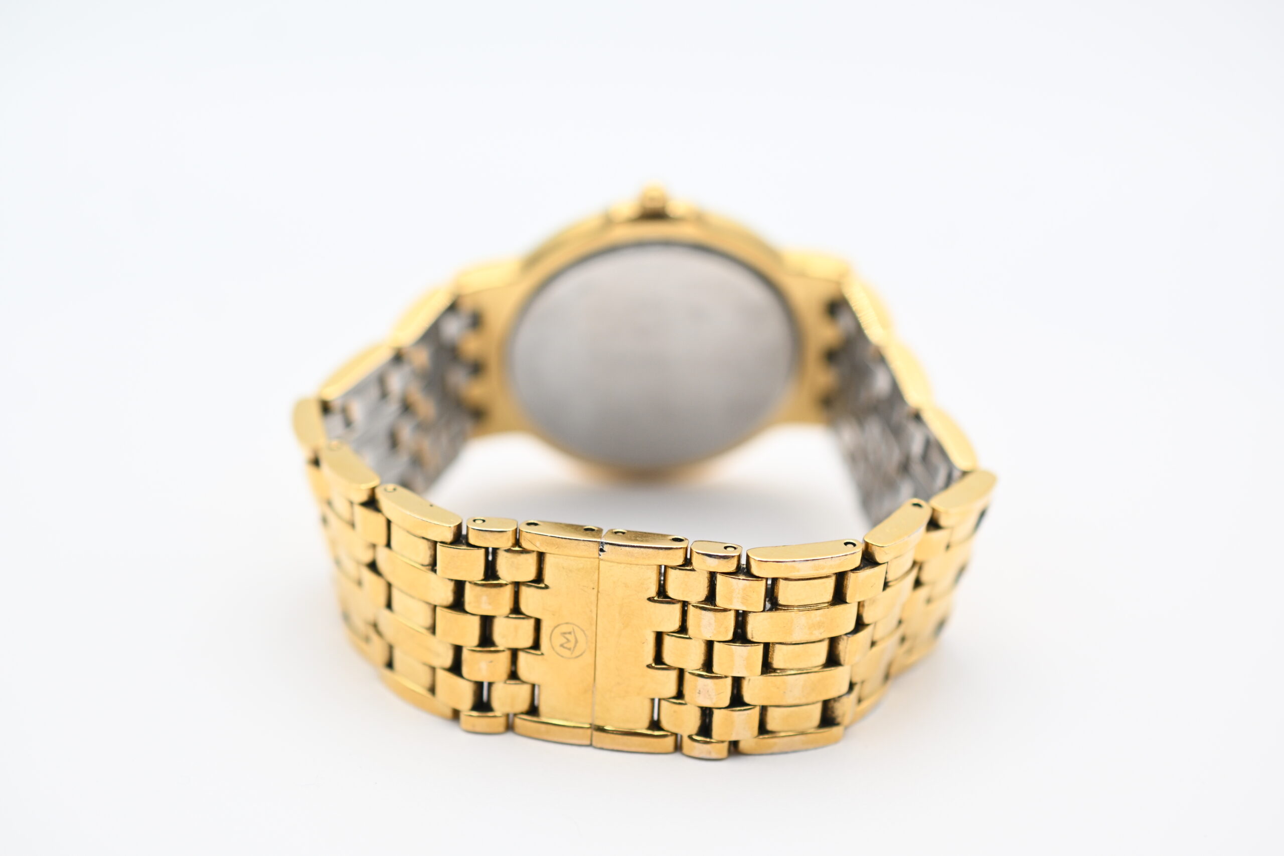 Back view of the Movado watch case showing the plain gold-tone case back and folded clasp