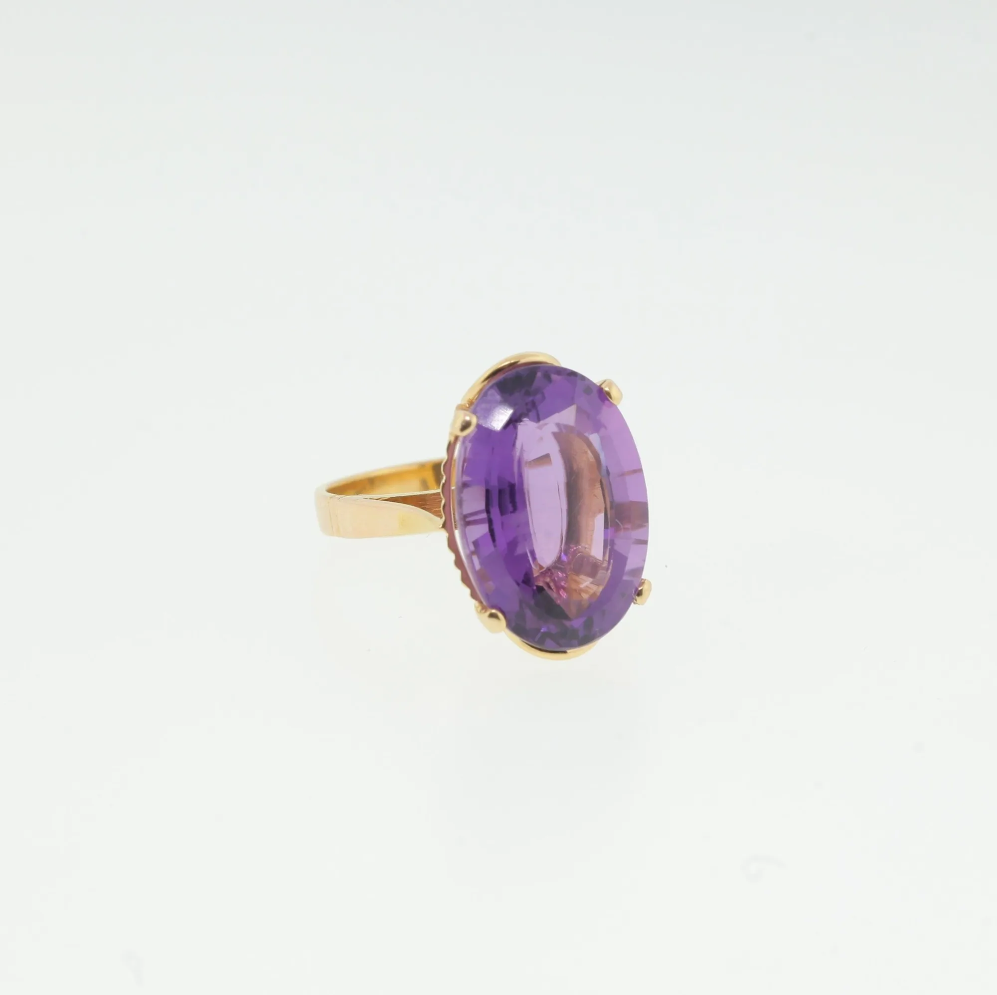 Front-facing angled view of oval purple stone ring on white background