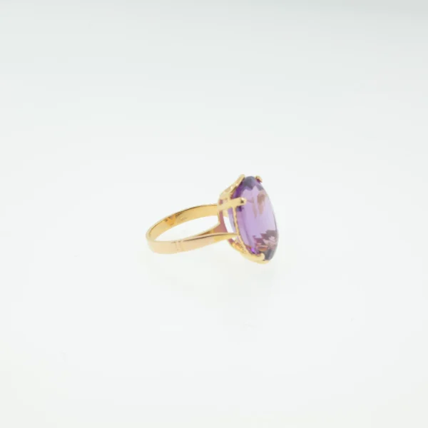 Side view of gold-tone ring with large oval purple stone in prong setting