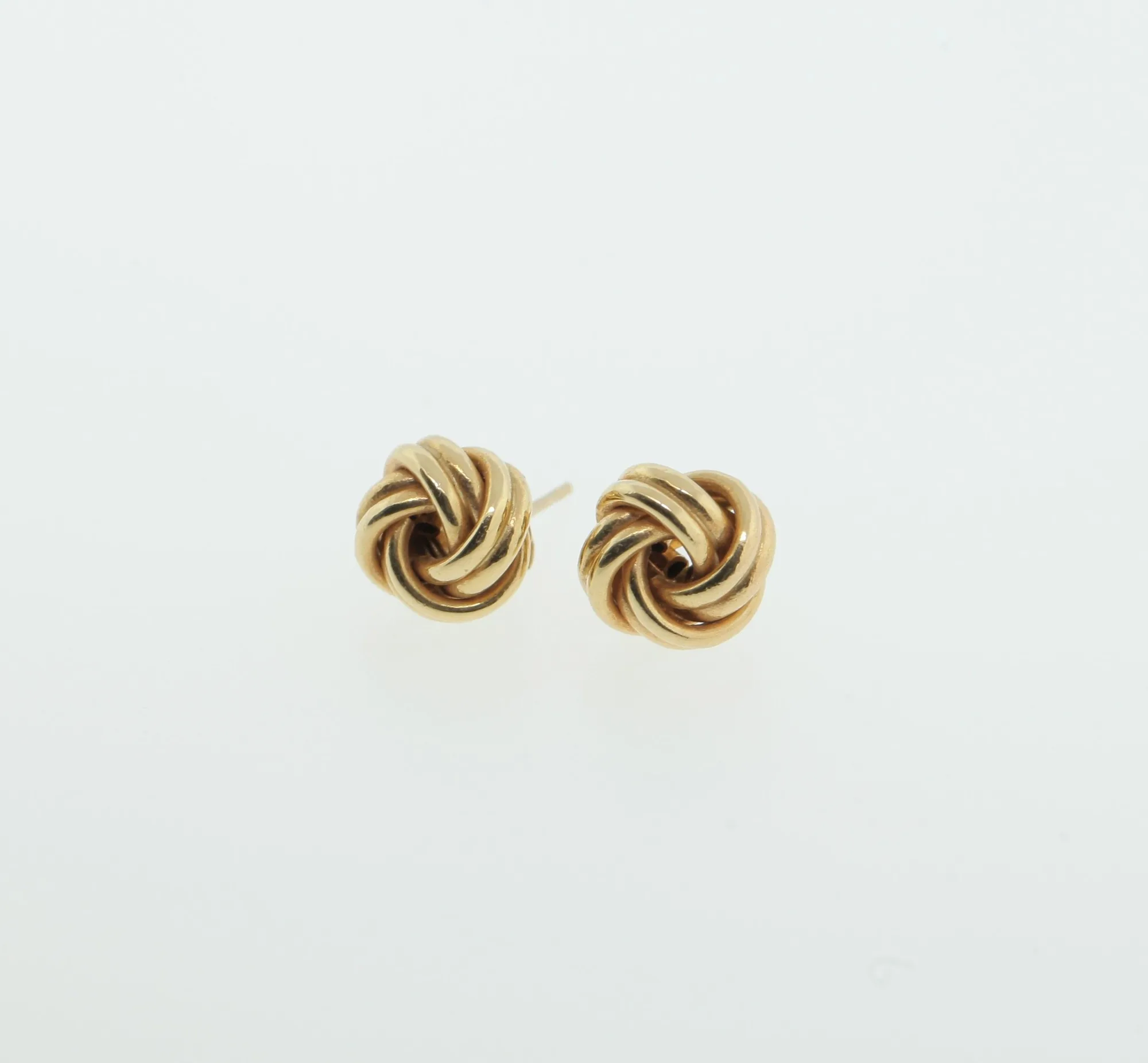 Close-up of gold-tone twisted wire knot earrings showing texture detail