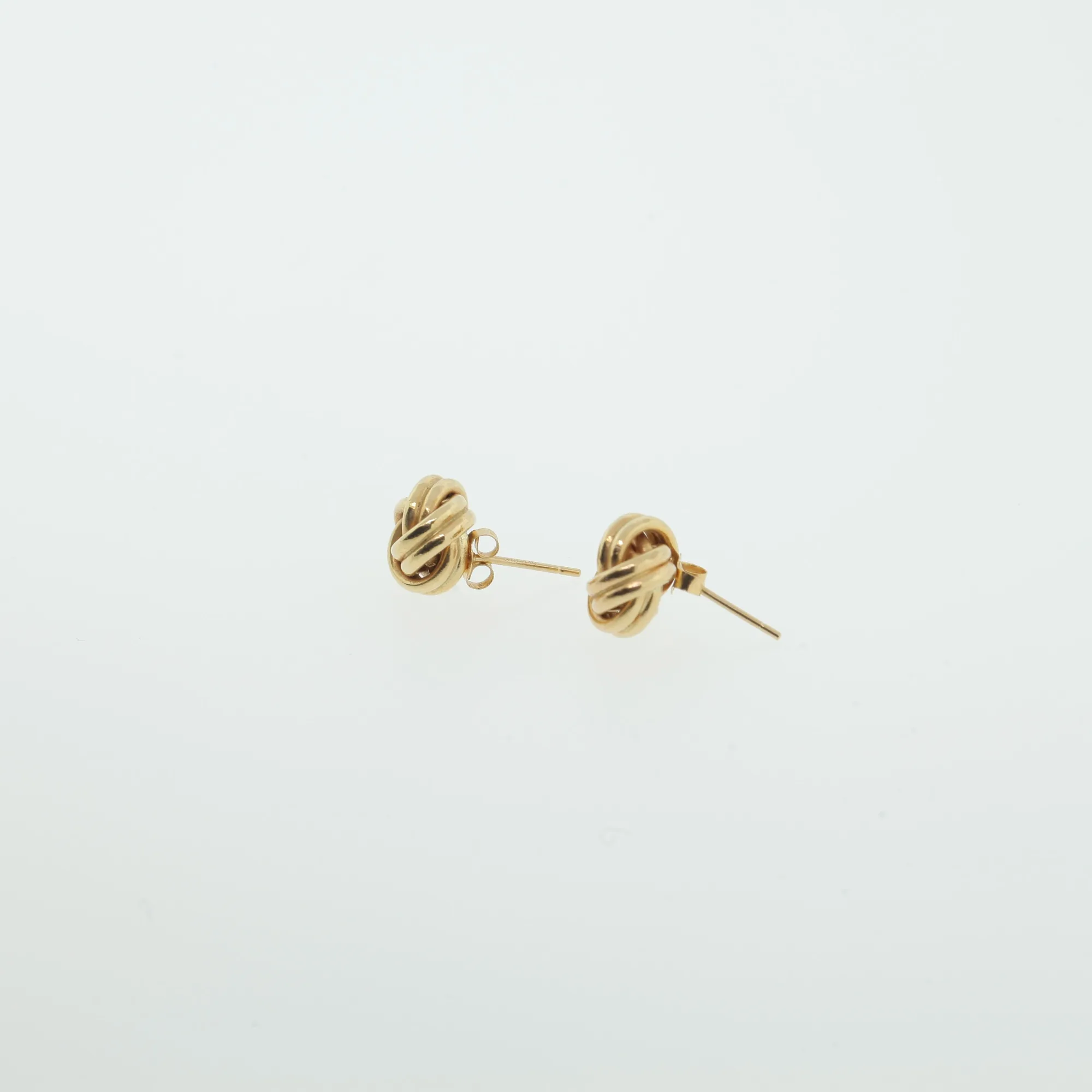 Gold-tone knot earrings laid at an angle highlighting posts and clutch backs