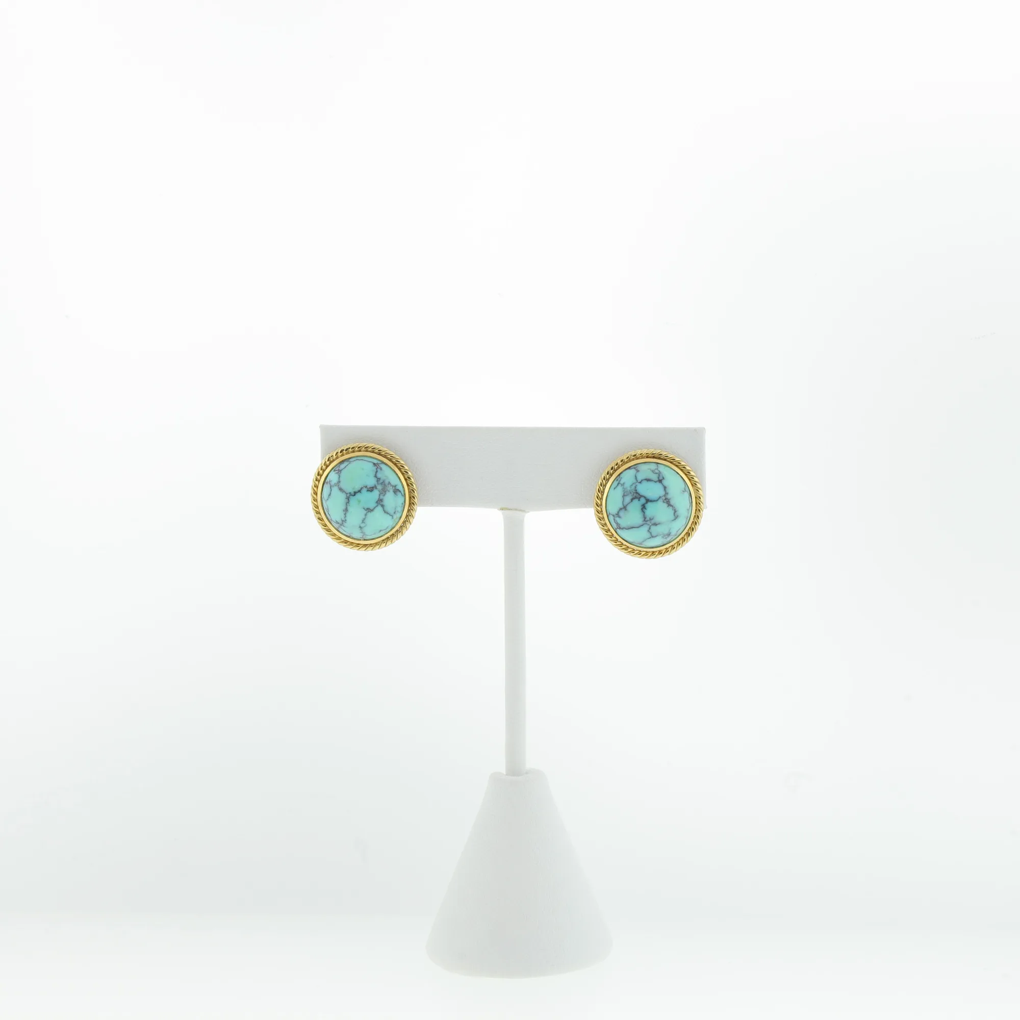 Front view of the paired earrings mounted on a white display stand