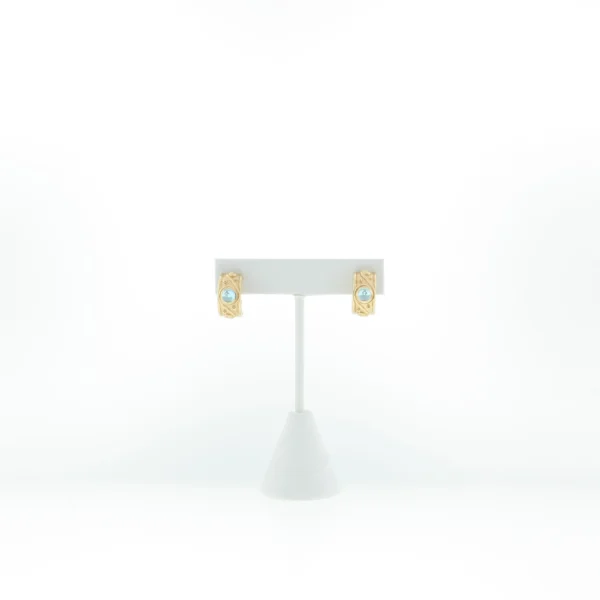 Front view of gold-tone scroll hoop earrings with light blue cabochon stones on a T-bar display stand