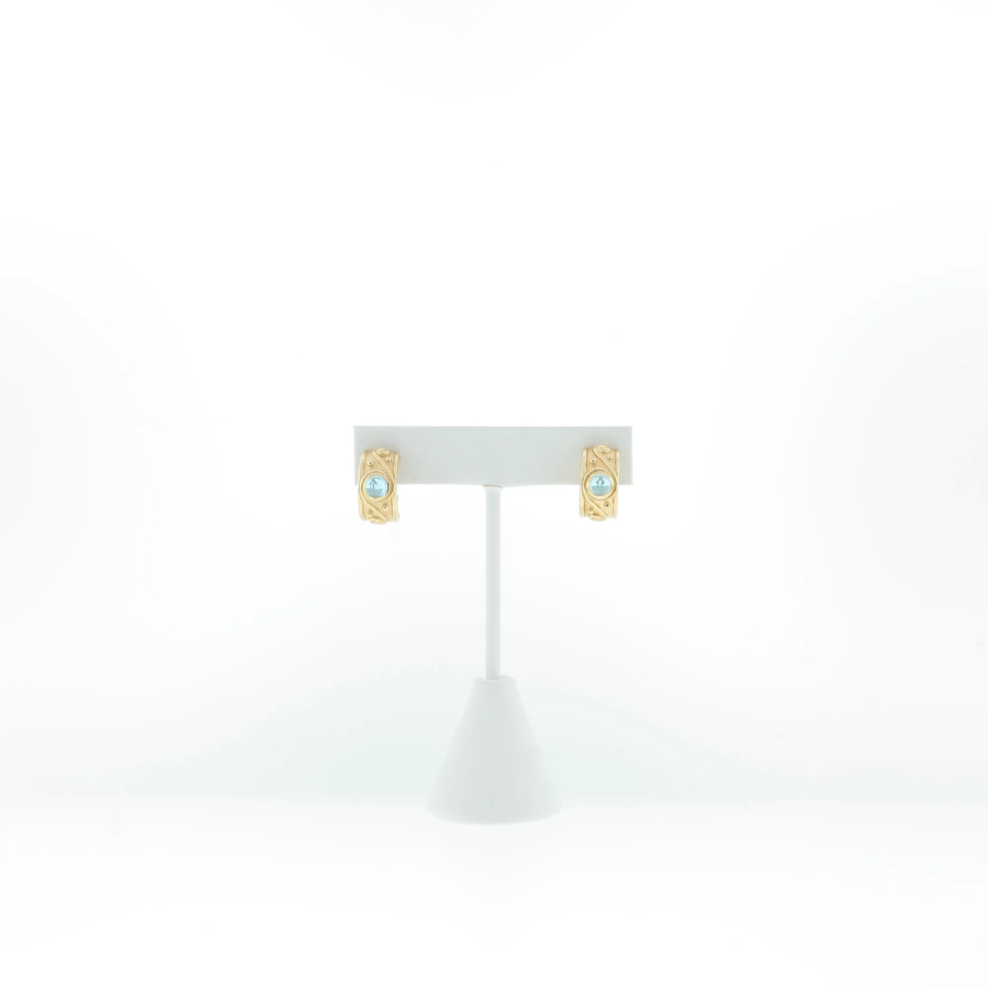 Front view of gold-tone scroll hoop earrings with light blue cabochon stones on a T-bar display stand