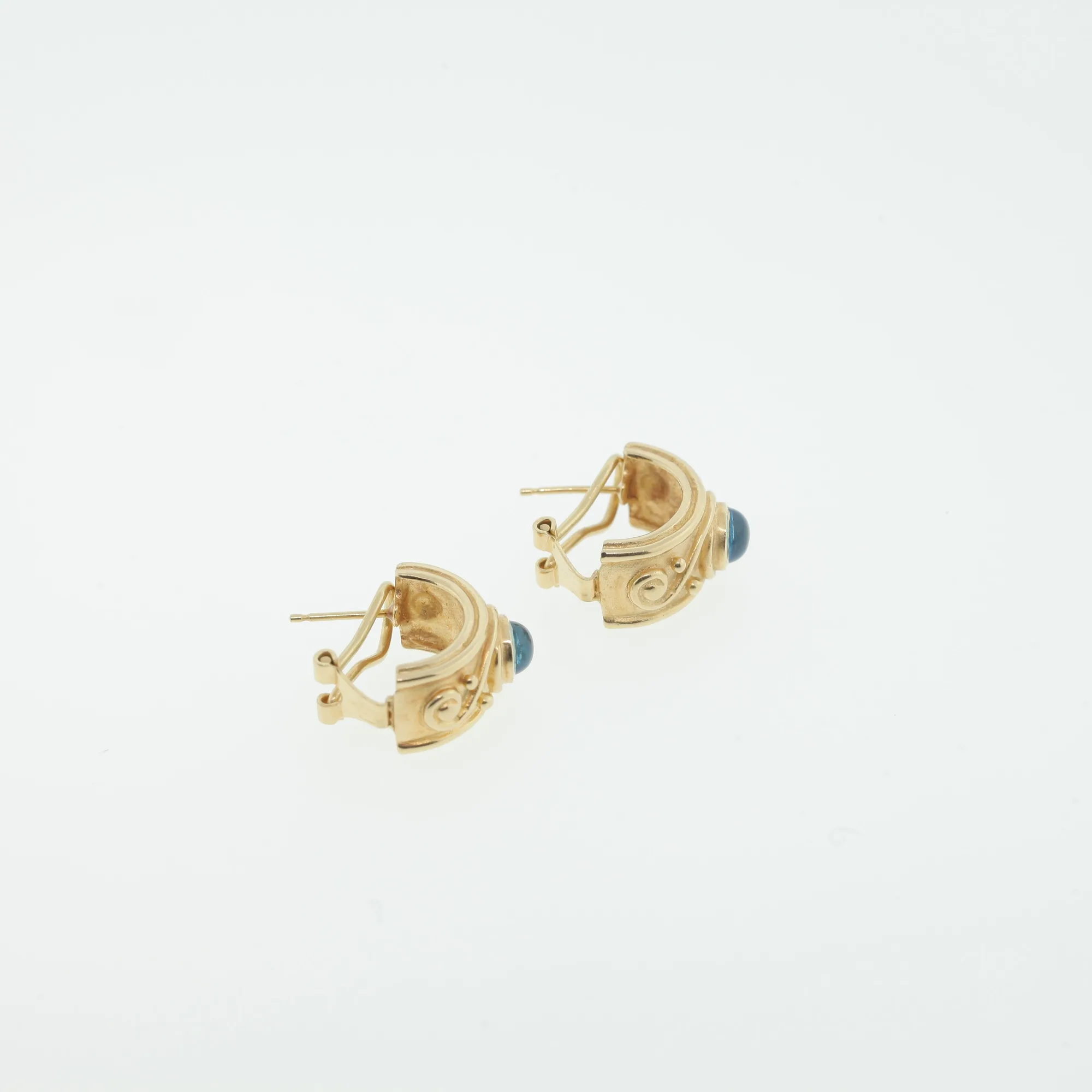 Angled view showing the omega clip backs and posts on both earrings with blue cabochon stones visible