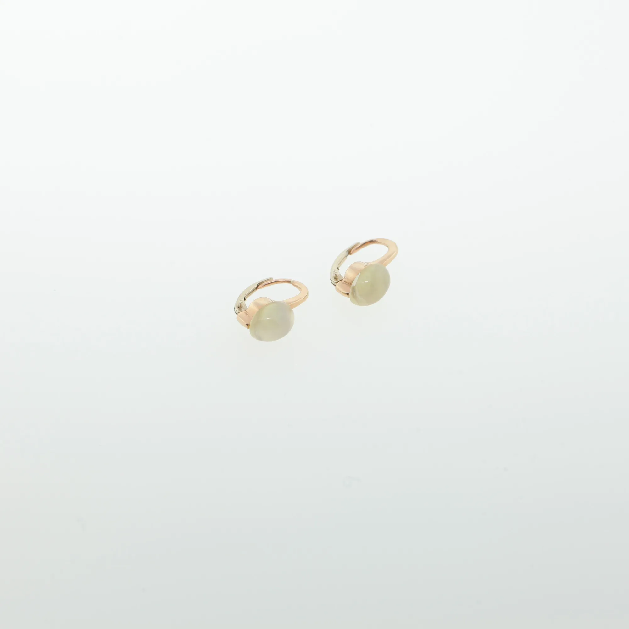 Close-up of rose gold-tone hoop earrings with pale oval cabochon stones on a white background