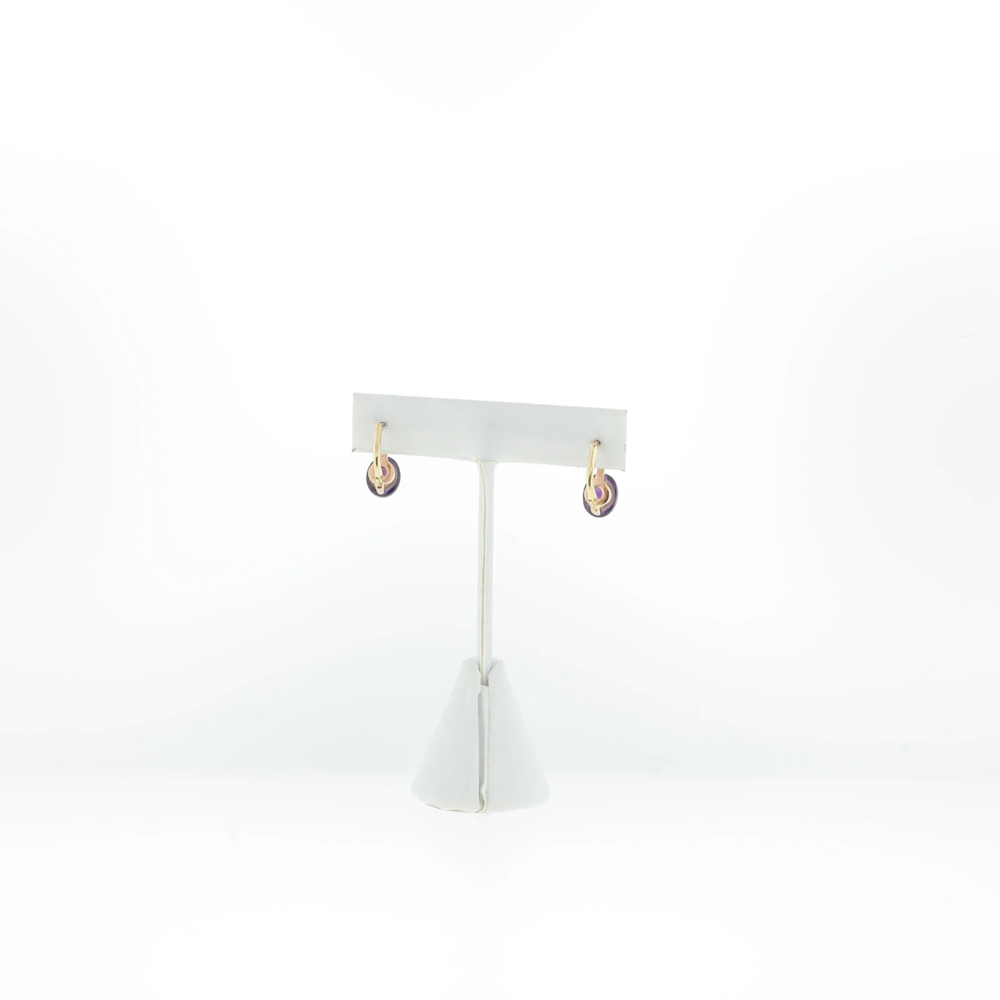 Angled view of the pair of purple cabochon drop earrings hanging from a jewelry display stand