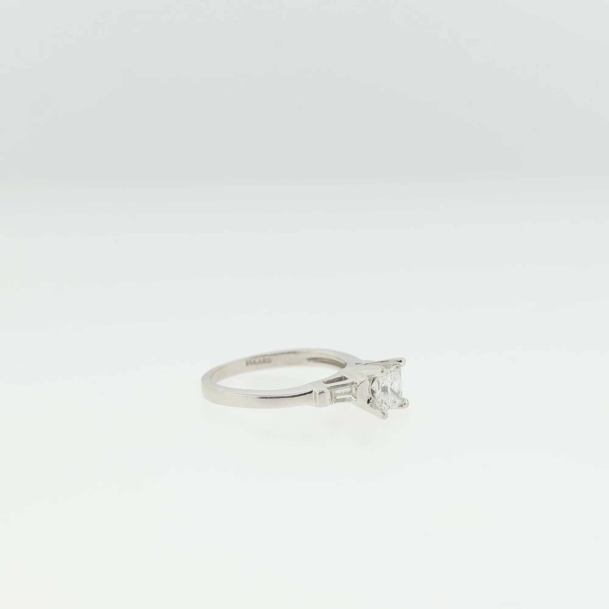 Angled side view of the ring showing the baguette side stones and cathedral-style shoulders