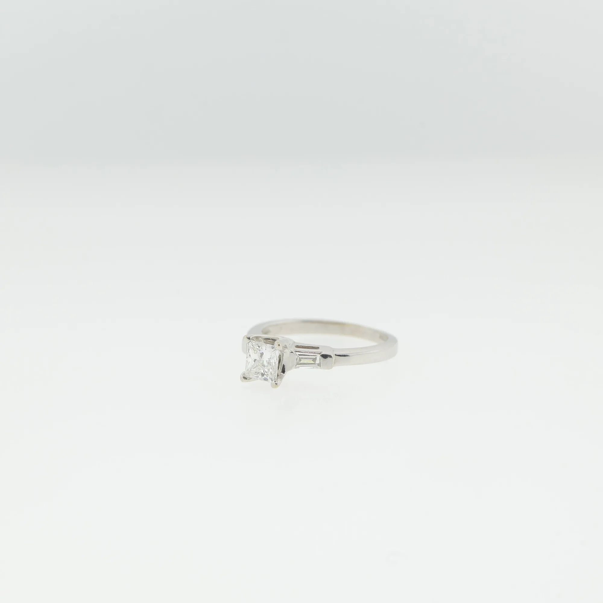 Front-facing view of the ring lying flat, showing the princess-cut center stone and setting
