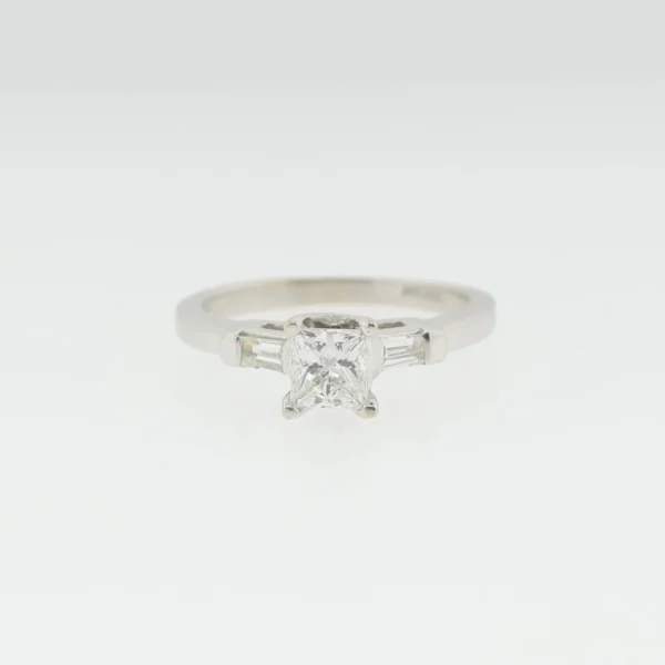 Front view of a white gold ring with a princess-cut center stone flanked by tapered baguette side stones