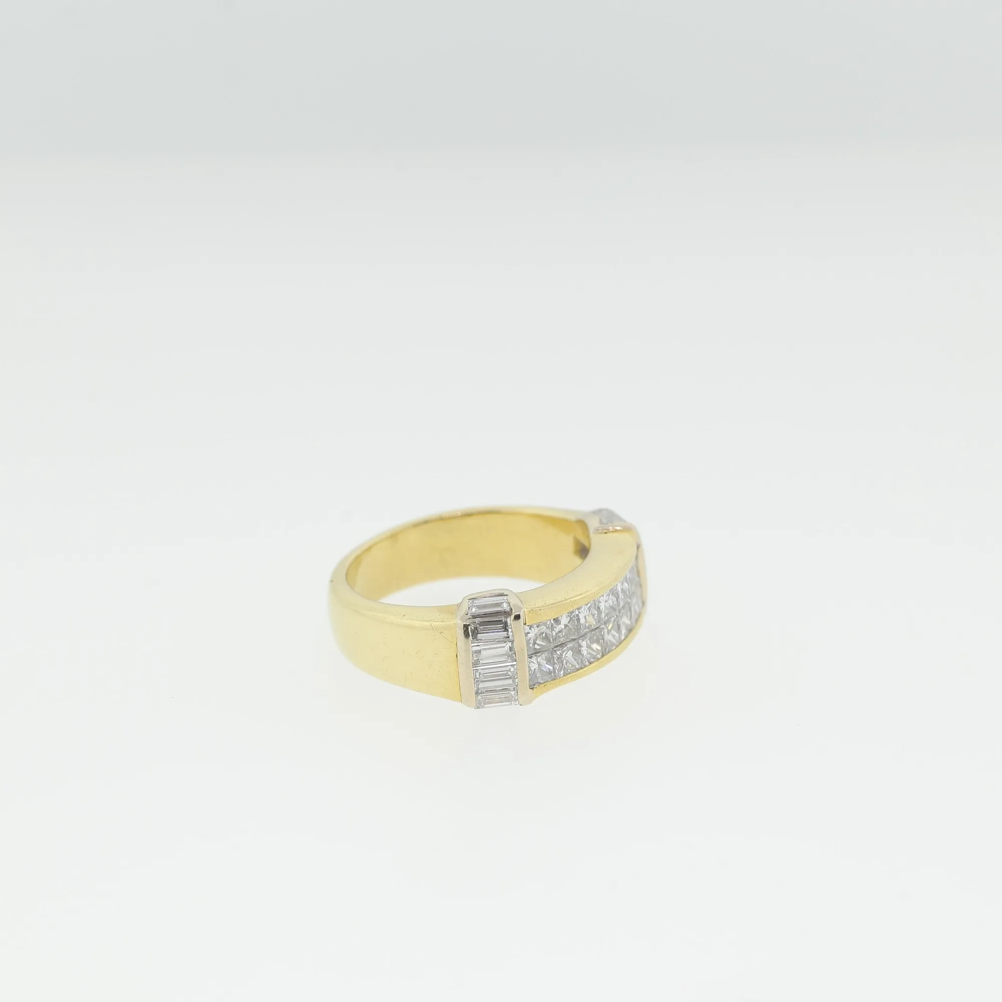 Angled view of the ring showing baguette-cut stones along the shoulder and polished gold shank