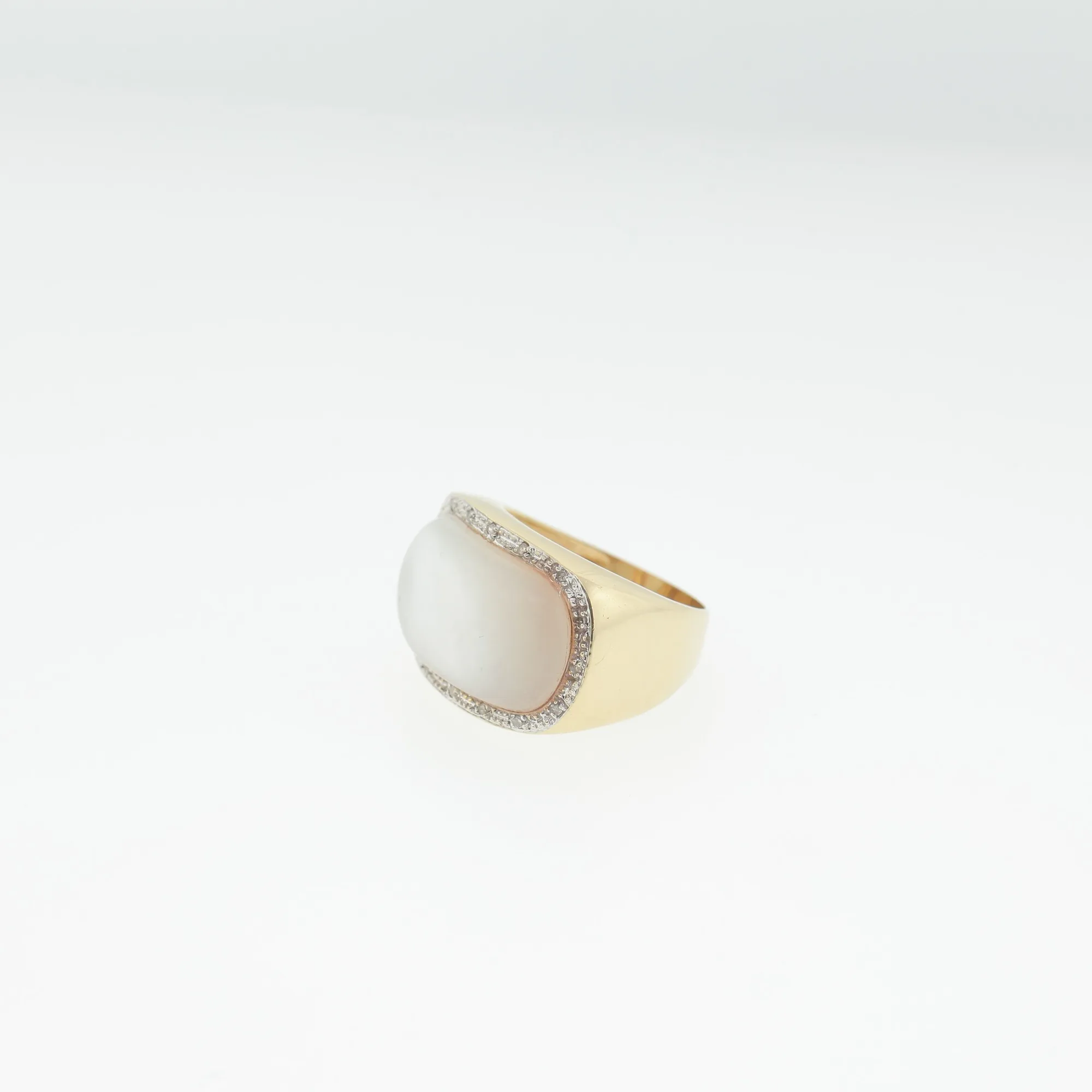 Three-quarter view of the ring showing the cabochon stone and pavé halo detail