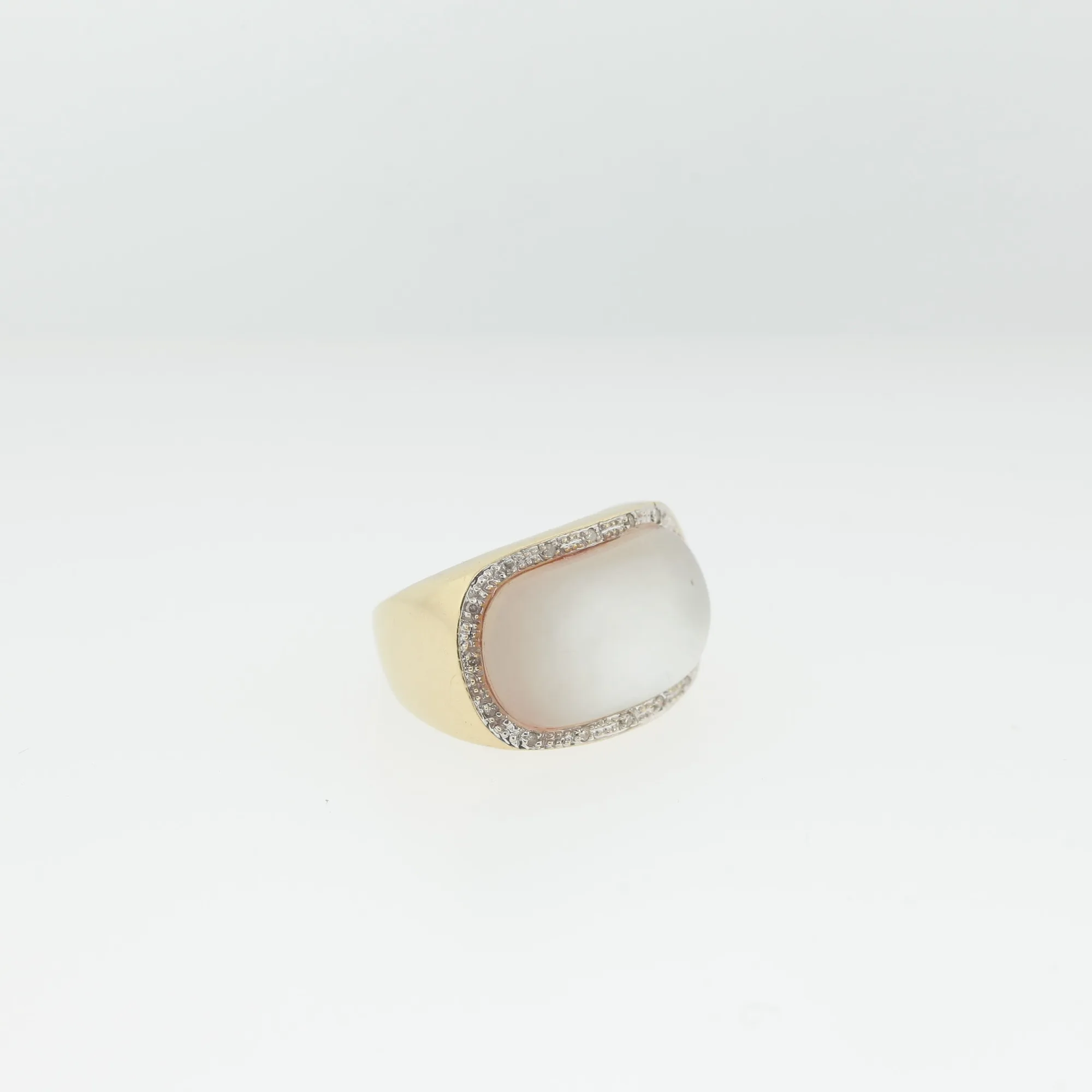 Angled view of a 14K gold ring with an oval cabochon stone bordered by small pavé stones