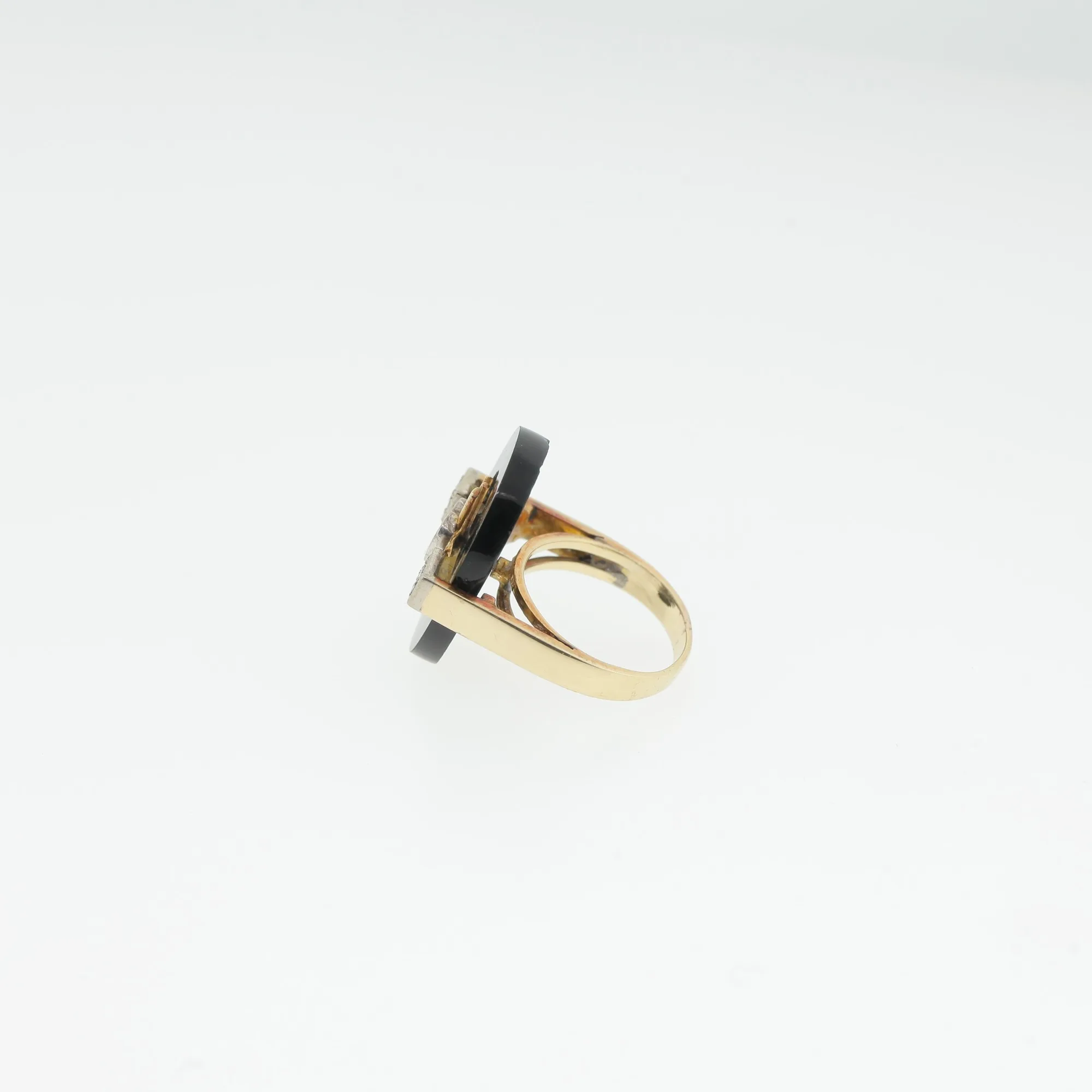 Side profile of a vintage cocktail ring showing the black stone disc and gold-tone band