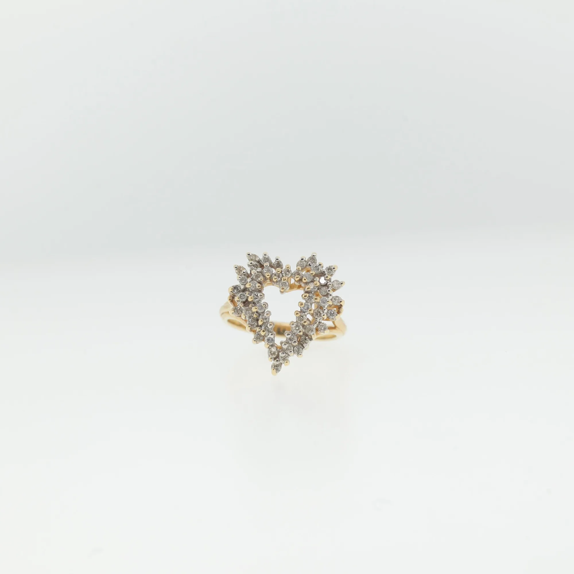 Front view of heart-shaped cluster ring with rows of small faceted clear stones on a gold-tone band