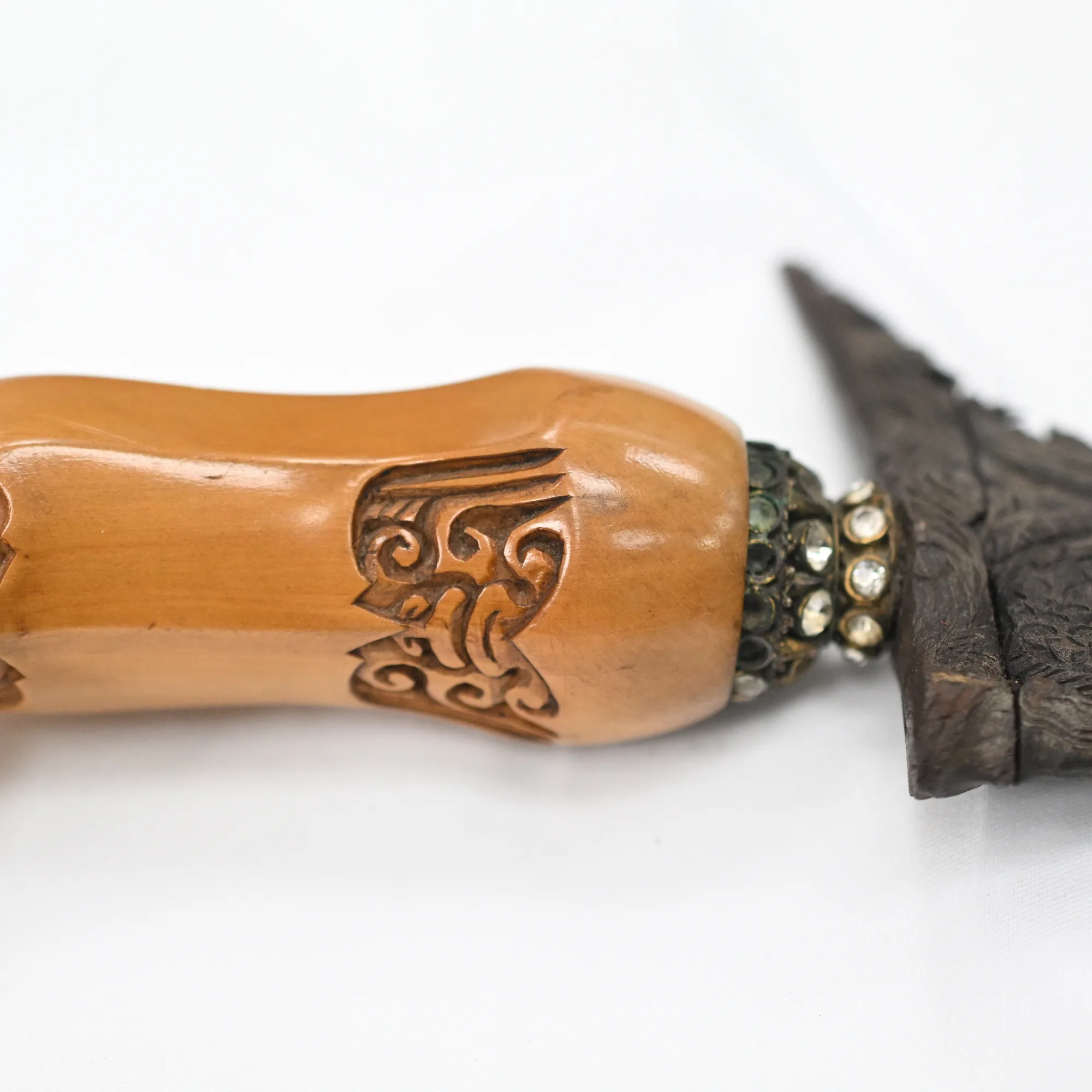 Close view of the carved honey-toned wood hilt